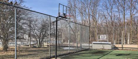 Una cancha de baloncesto con una valla de malla metálica, un aro de baloncesto y un cartel que indica una zona de pesca y patinaje sobre hielo.