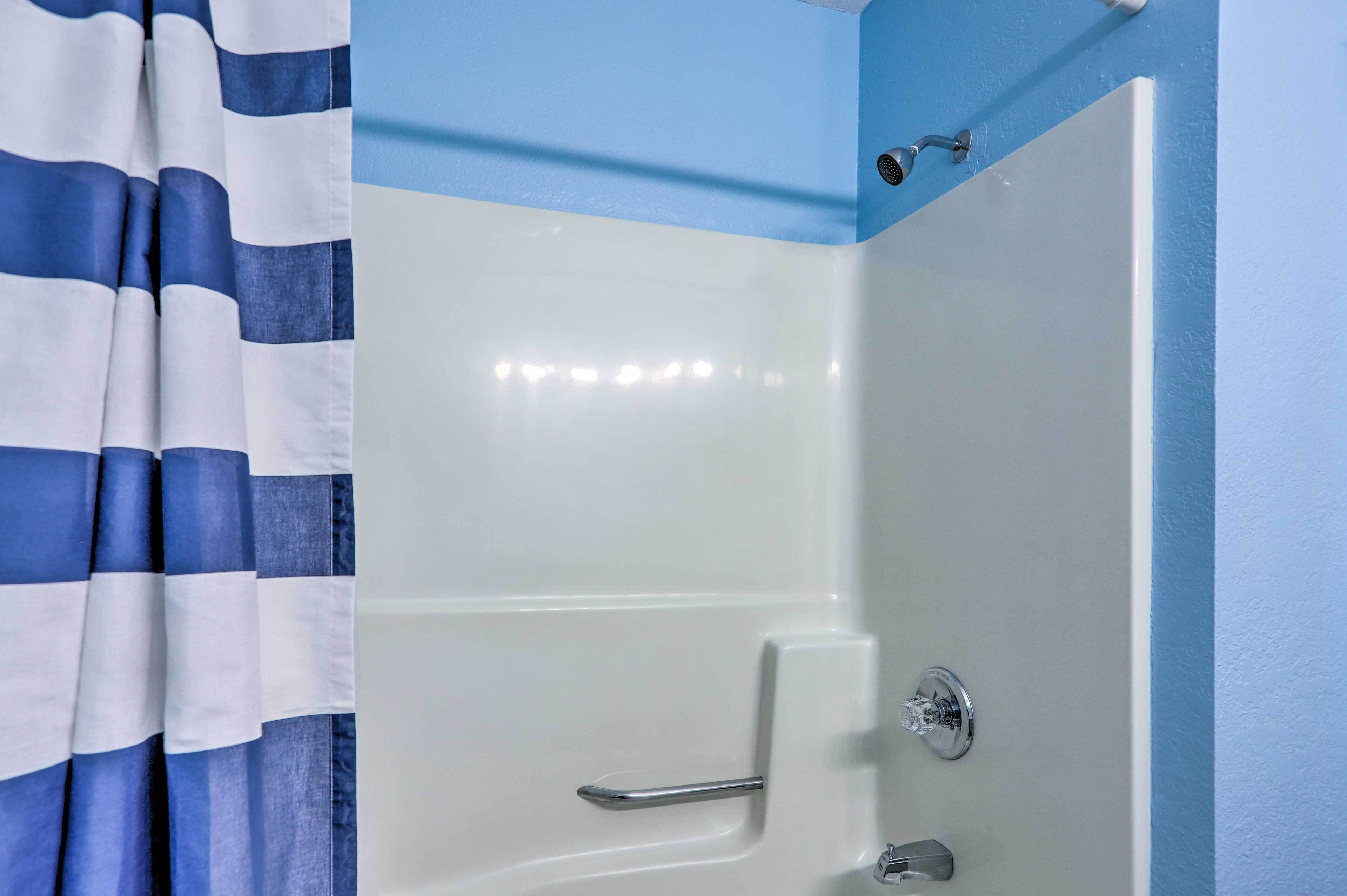 A bathroom with a white bathtub, a shower curtain, and a blue wall.