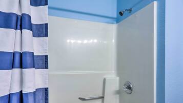 A bathroom with a white bathtub, a shower curtain, and a blue wall.
