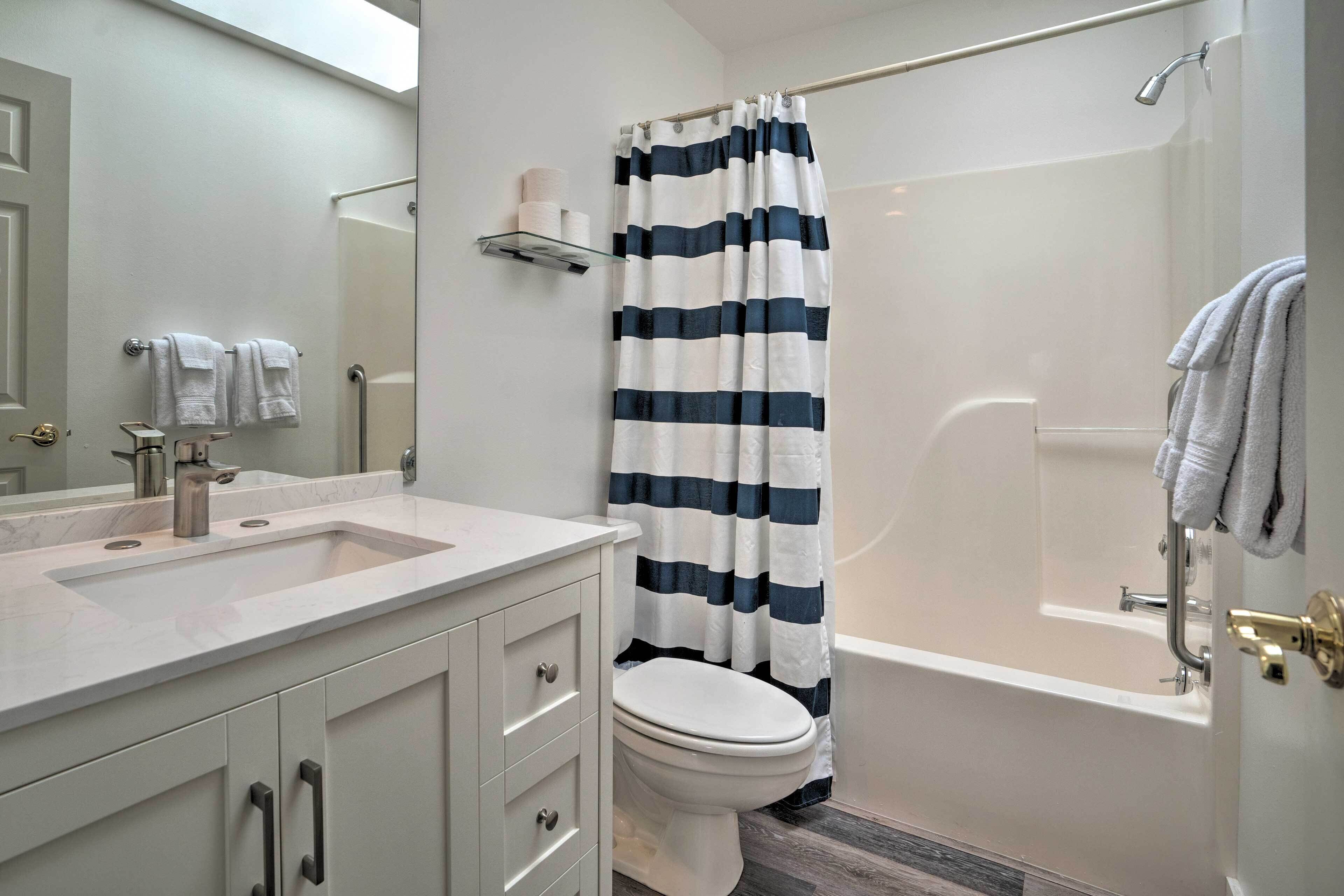 Un baño con lavamanos blanco, inodoro, bañera y cortina de ducha.