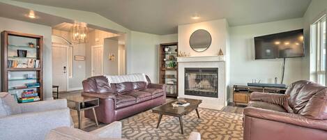 A living room with a fireplace, leather sofas, a coffee table, and a bookshelf.