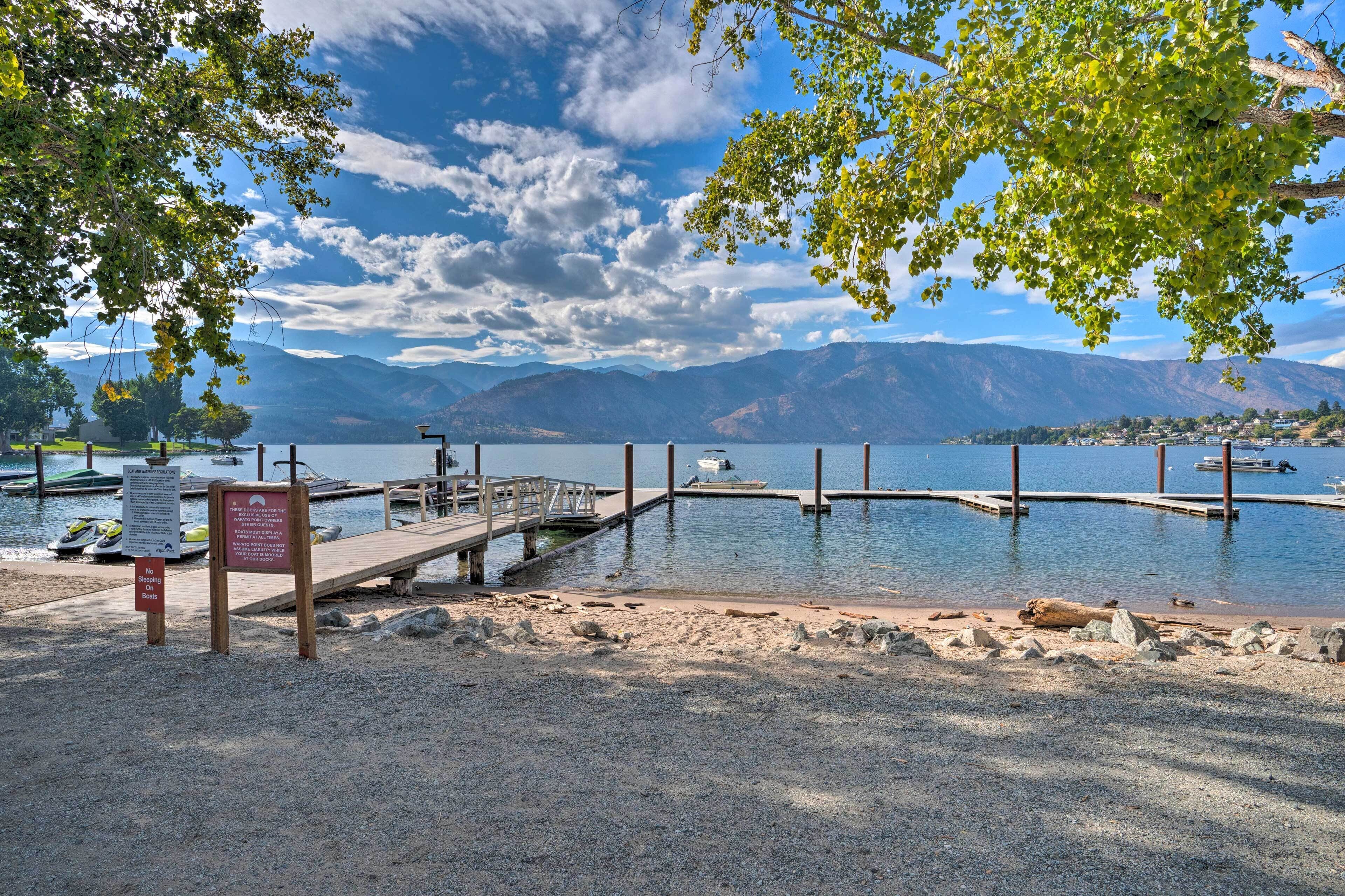 Une jetée en bois au bord du lac, avec des bateaux amarrés et un panneau indiquant qu’il est interdit de se baigner.