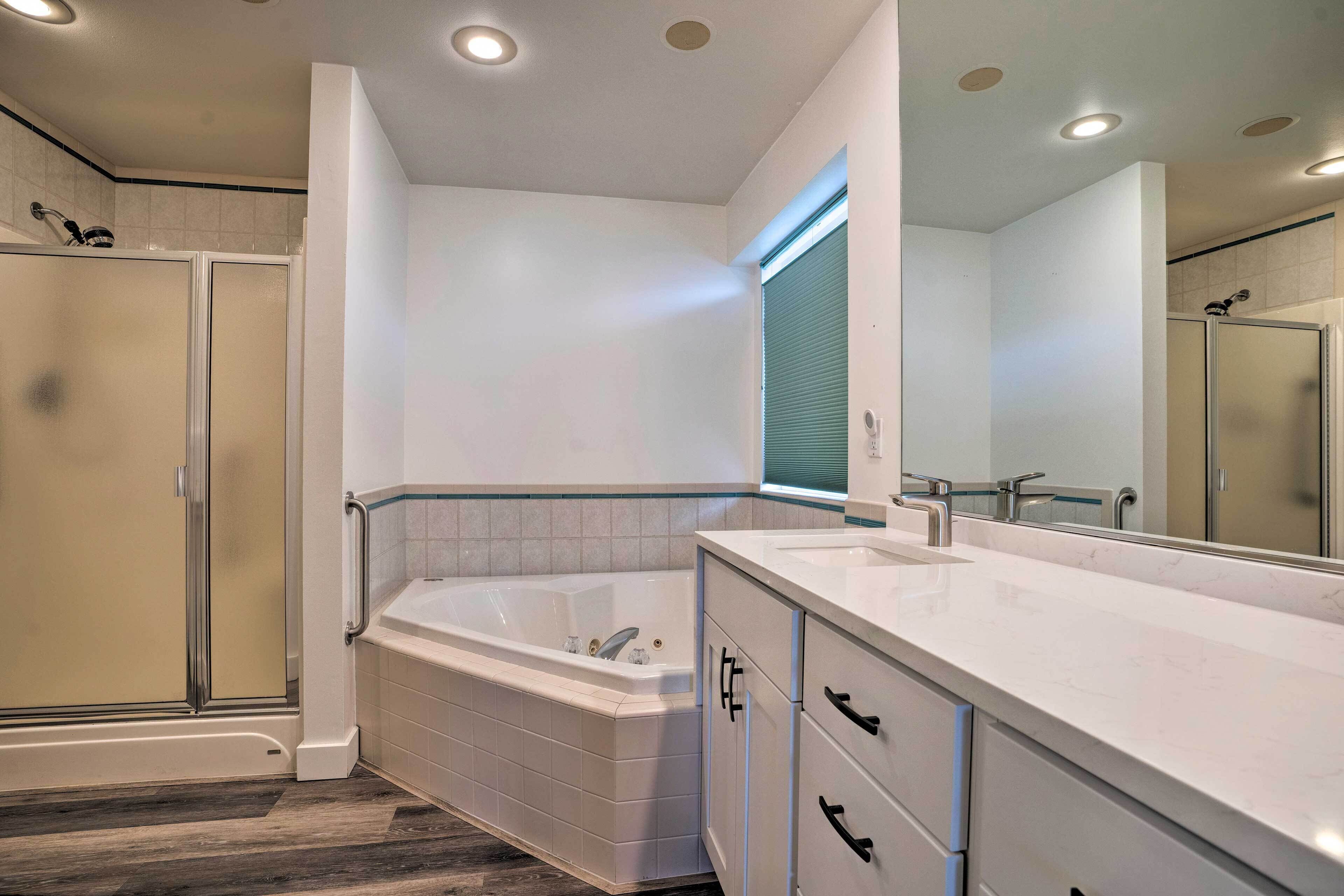 A modern bathroom with a walk-in shower, a freestanding bathtub, and a vanity with a large mirror.