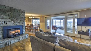 Ein Wohnzimmer mit Kamin aus Stein, einem großen grauen Sofa und einem Fernseher.