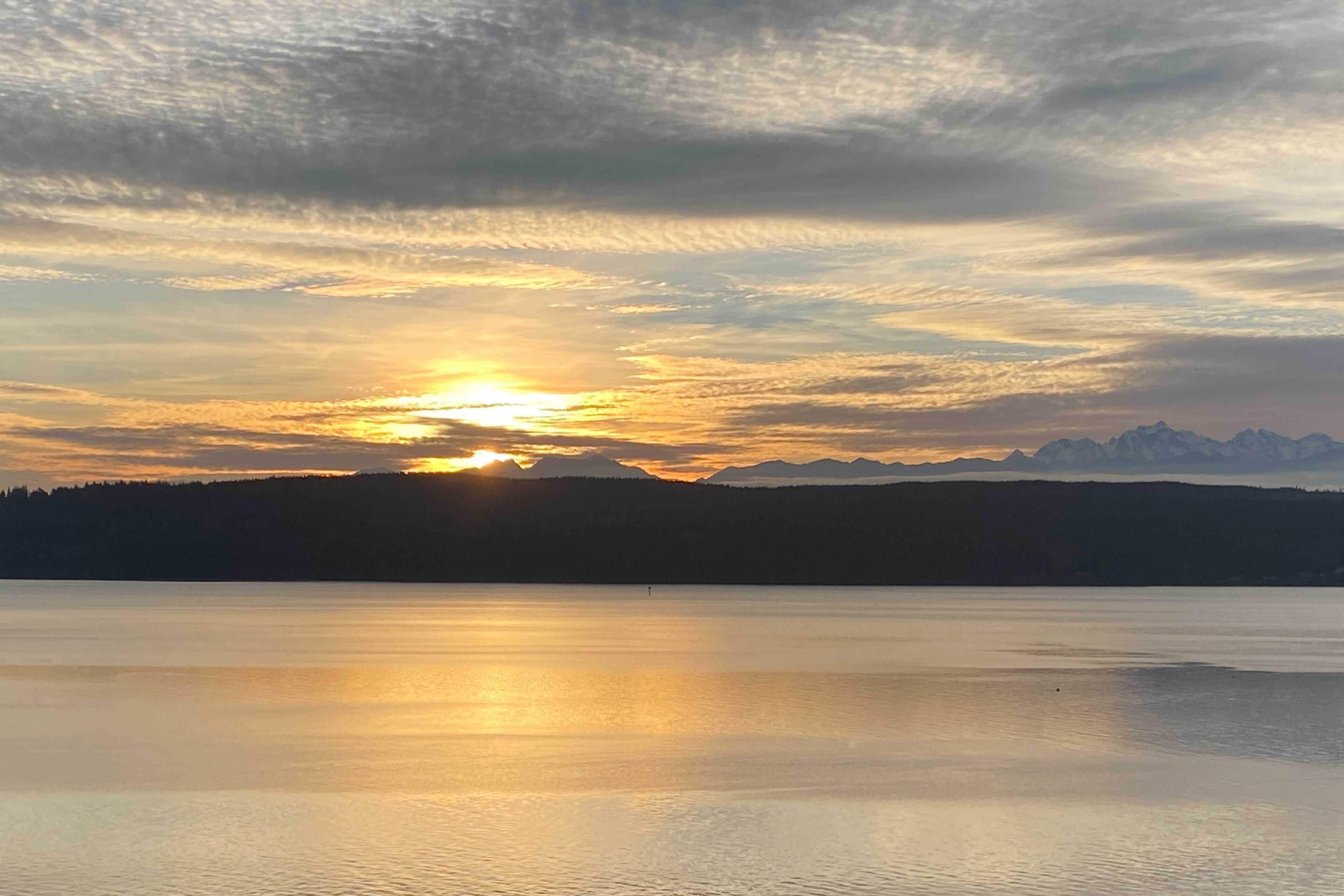 Een rustig meer bij zonsondergang met bergen op de achtergrond.