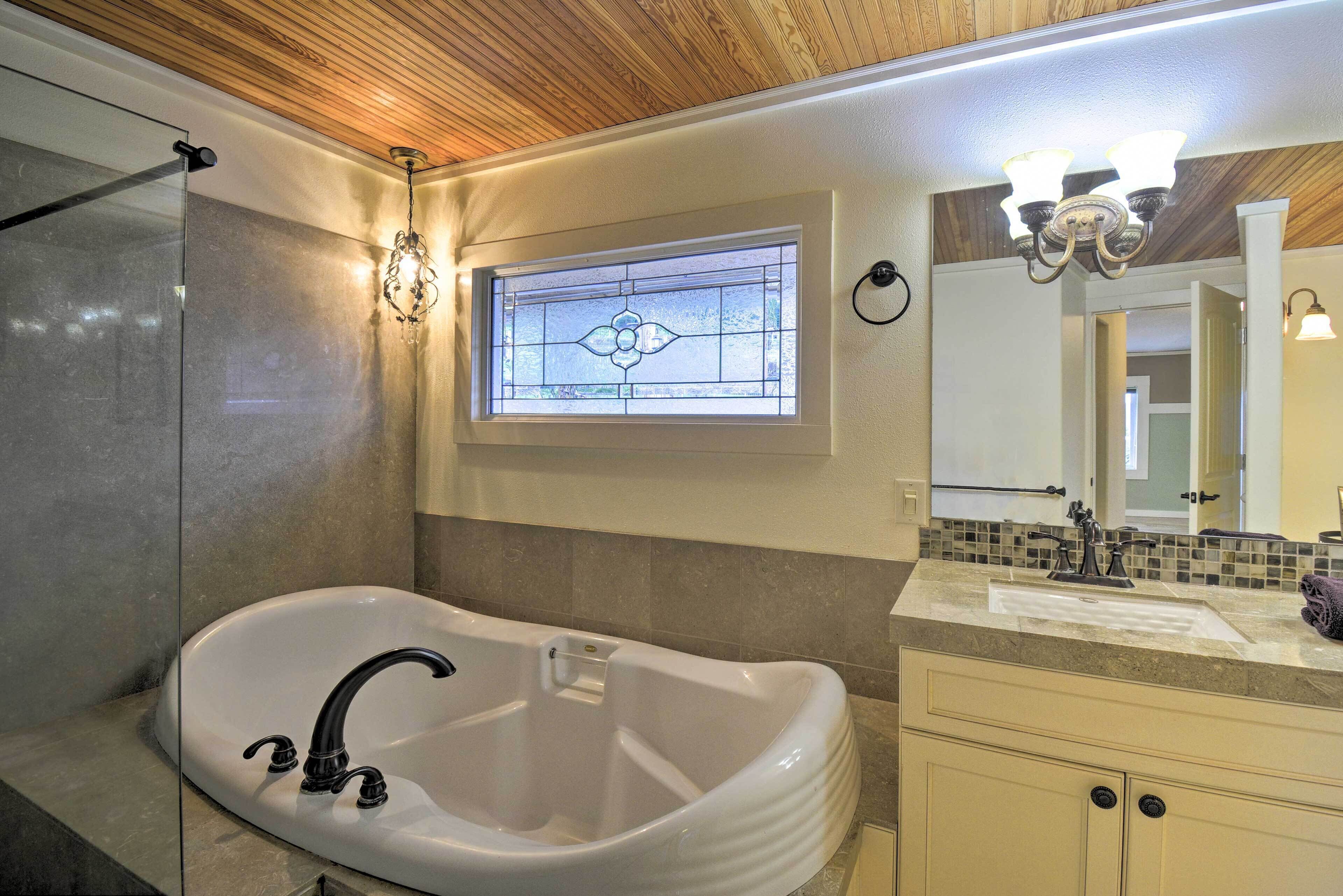 A bathroom with a freestanding bathtub, a glass shower enclosure, and a vanity with a mirror.