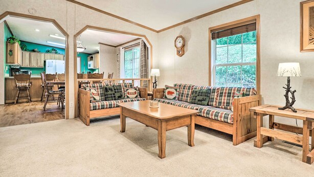 A cozy living room with a wooden coffee table, a plaid sofa, and a matching bench. There is a dining area with a wooden table and chairs, and a kitchen visible through an archway. - Franklin Home w/ Deck, & Fire Pit: 8 Mi to Dtwn! (Franklin)