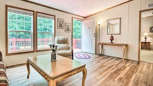 A spacious room with large windows, a wooden floor, a beige armchair, a coffee table, and a door leading outside. - Franklin Home w/ Deck, & Fire Pit: 8 Mi to Dtwn! (Franklin)