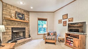 A cozy living room with a stone fireplace, a comfortable chair, a television on a wooden stand, and a bookshelf. - Franklin Home w/ Deck, & Fire Pit: 8 Mi to Dtwn! (Franklin)
