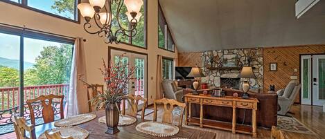 A spacious living room with a dining area, large windows, and a fireplace.