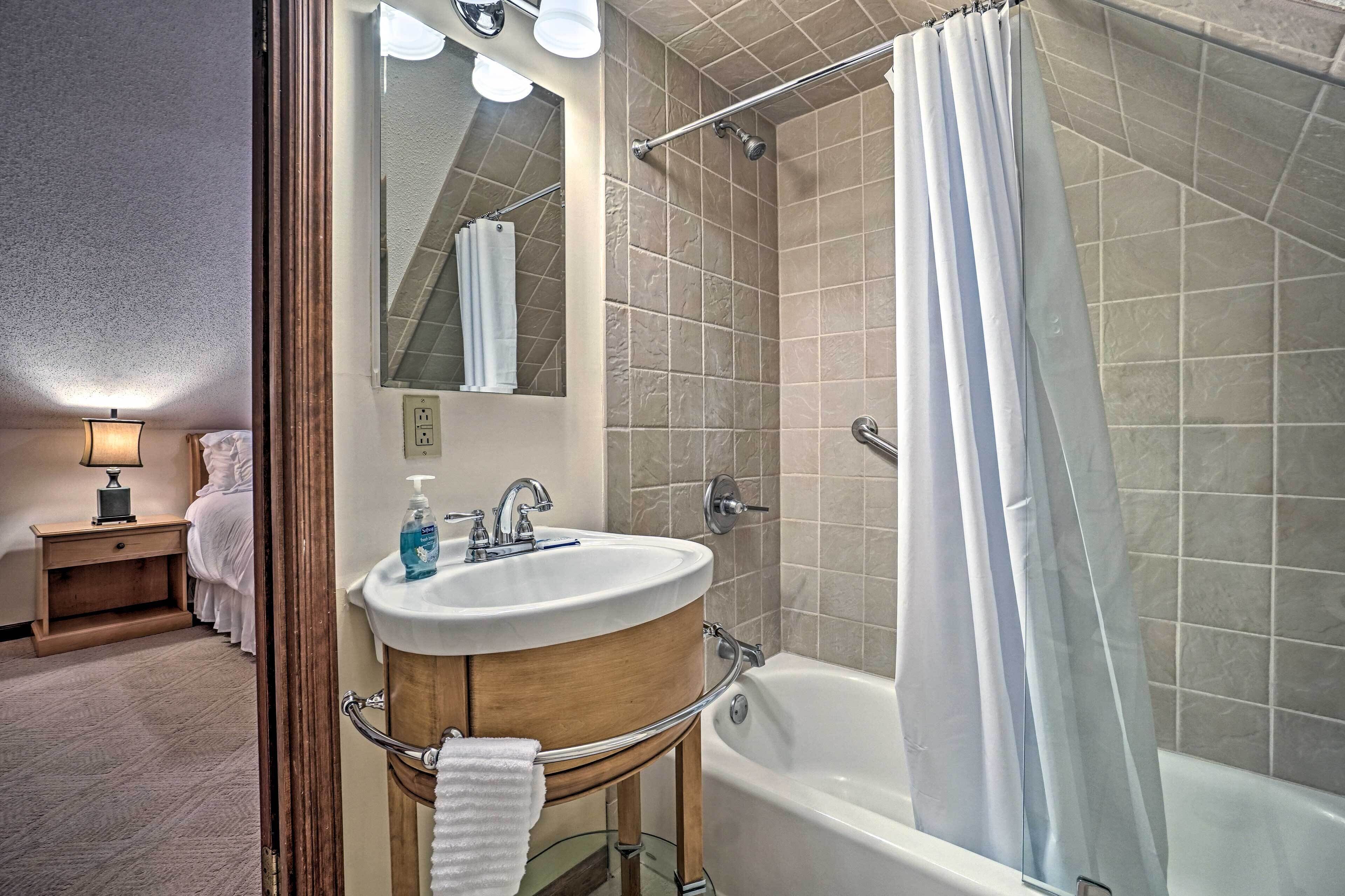 A bathroom with a bathtub, a sink, a mirror, and a shower curtain.