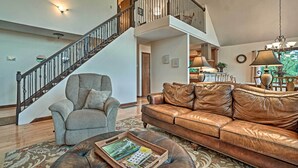 Ein geräumiges Wohnzimmer mit einer Ledersofa, einem gemusterten Teppich und einer Treppe, die zu einer oberen Ebene führt.