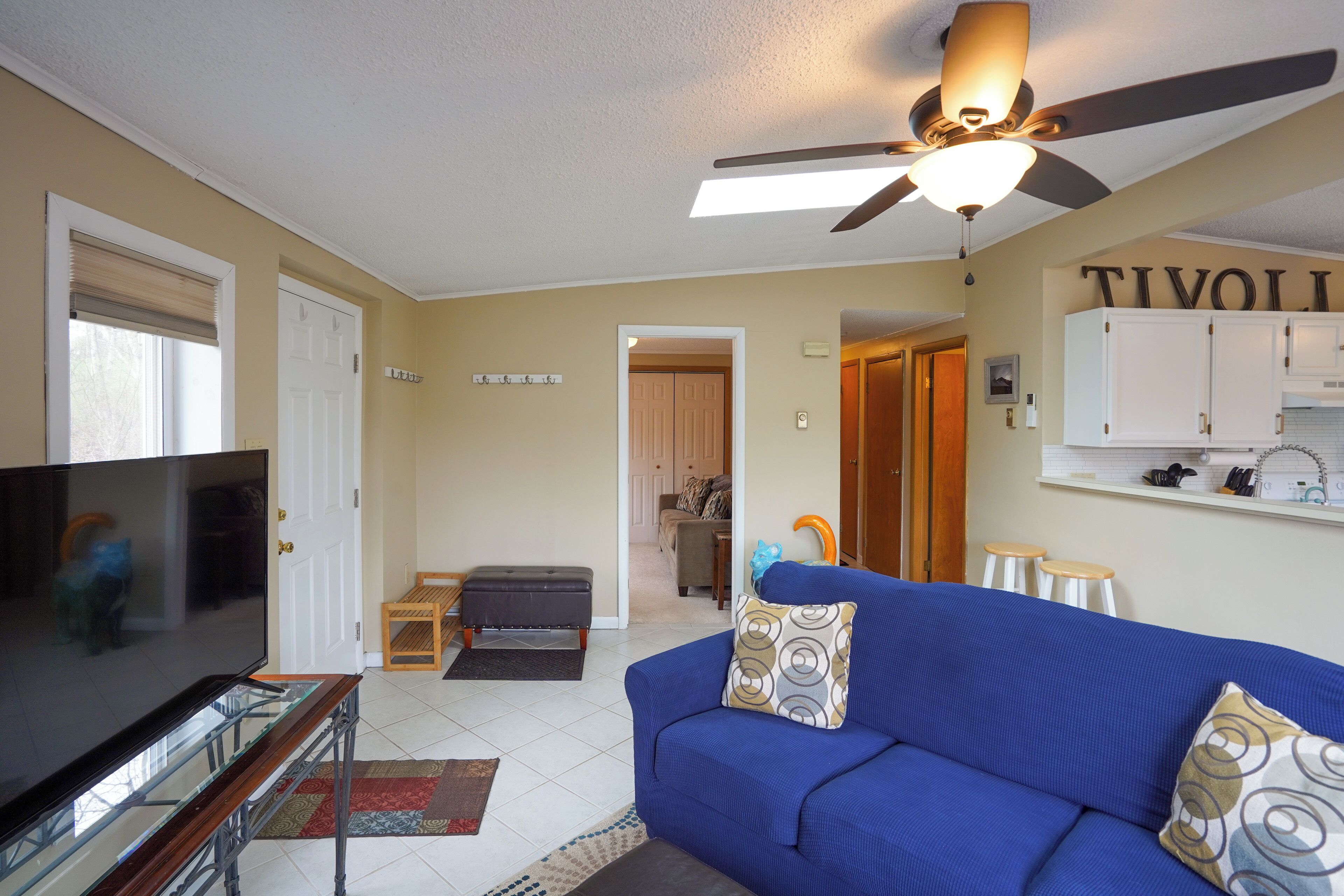 A living room with a TV, blue sofa, and a ceiling fan.
