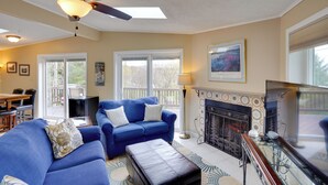 A living room with a blue sofa, a fireplace, and a ceiling fan.