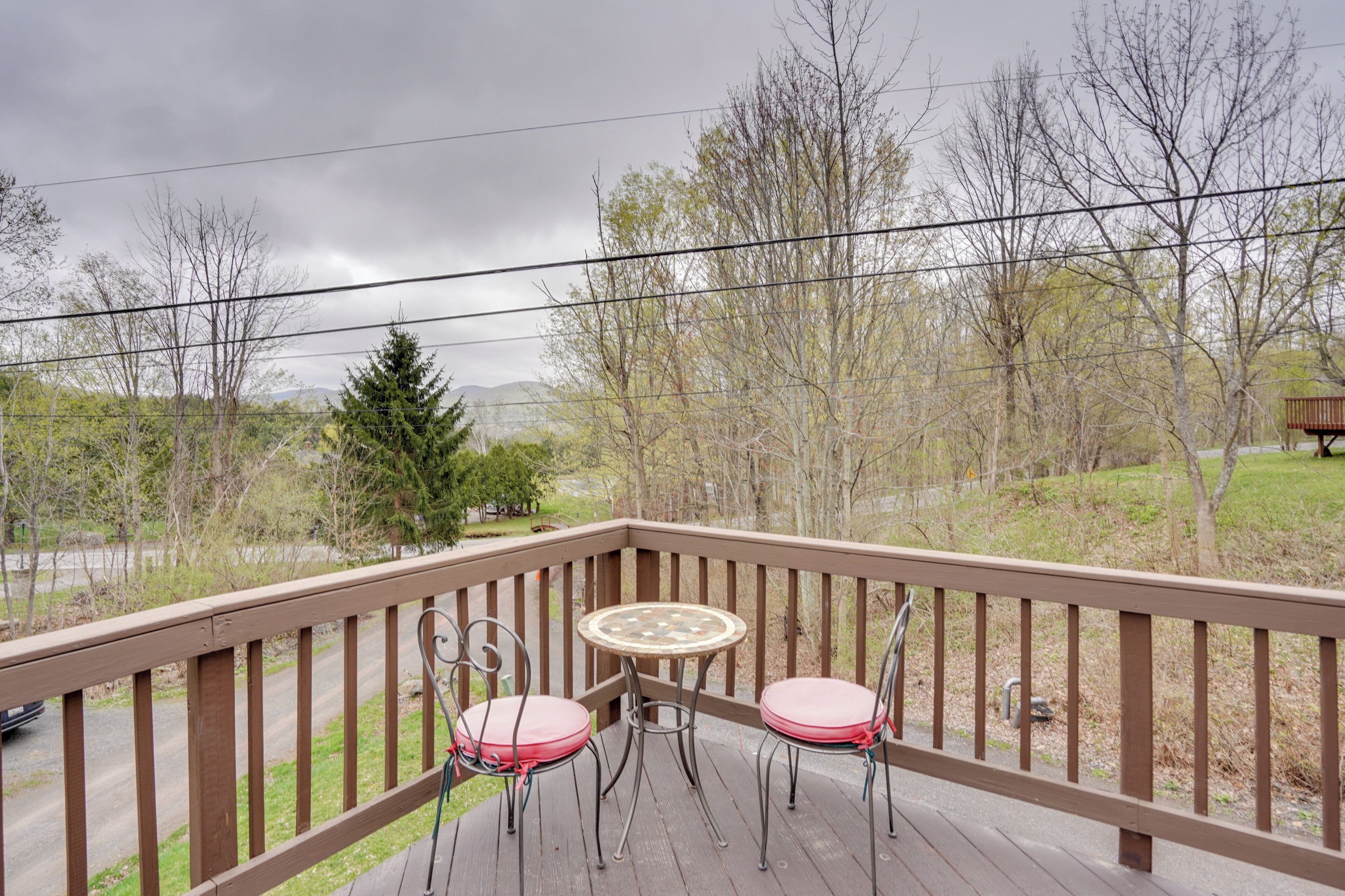 A wooden deck with two metal chairs and a small round table.