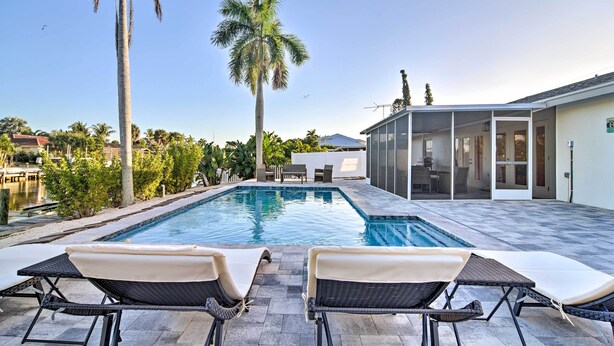 A swimming pool with lounge chairs, palm trees, and a modern house in the background. - Beach House w/ Pool: 3 Mi to Anna Maria Island! (Bradenton)