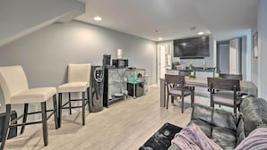 A modern living room with a sofa, two chairs, a coffee machine, and a TV mounted on the wall. - 6 Mi to National Mall: Modern DC Apartment! (Washington)