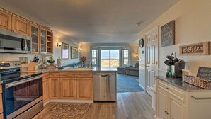 A modern kitchen with wooden cabinets, stainless steel appliances, and a dishwasher. There is a large window providing a view of the outdoors. - Eagles View Condo in Ocean Shores w/ 3 Balconies (Ocean Shores)