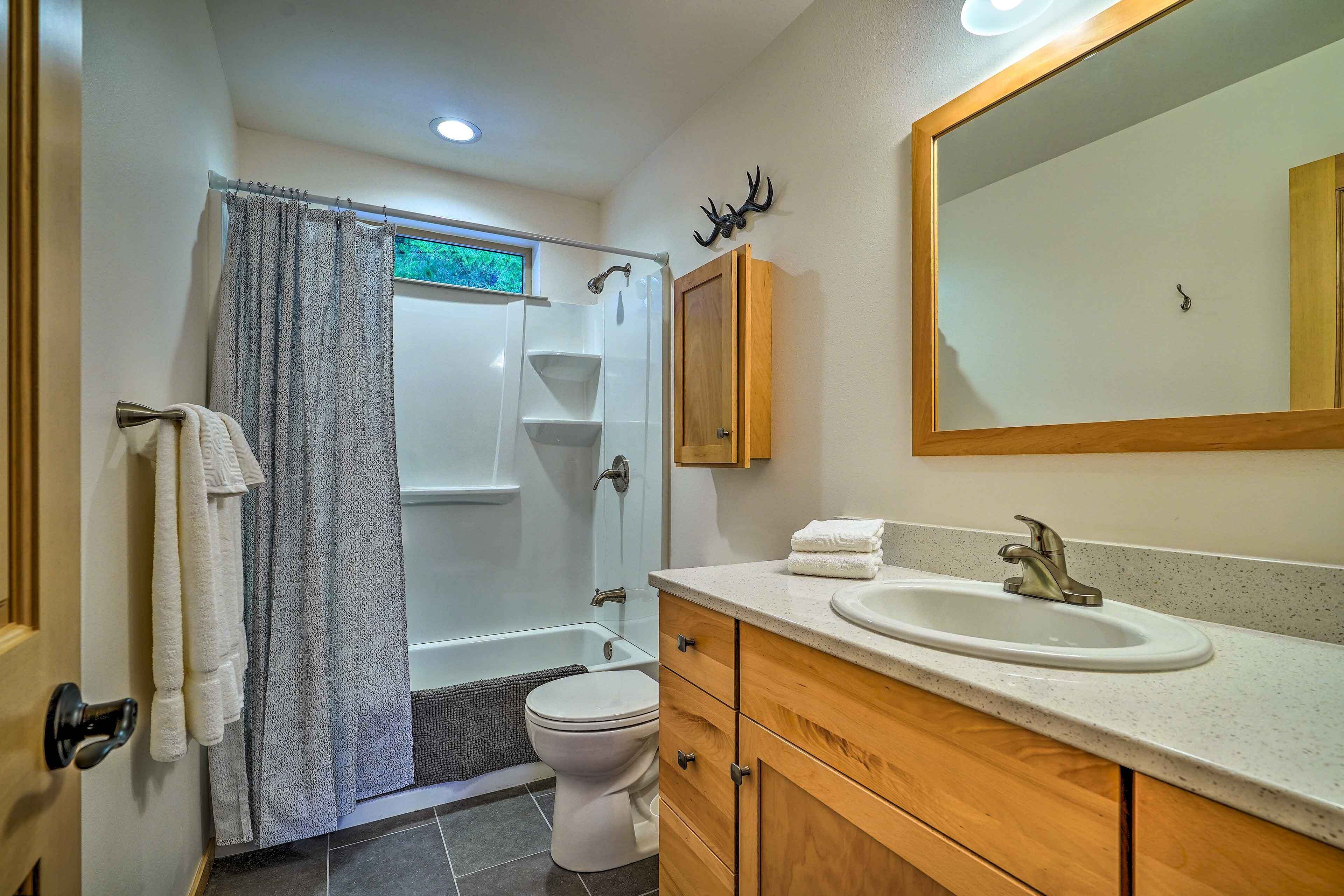 A bathroom with a shower, toilet, vanity with a sink, and a mirror.