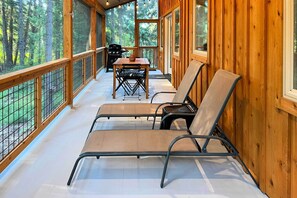 Una terraza de madera con una mesa y sillas, con vista a un bosque.