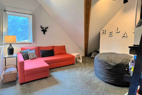 Un salon chaleureux avec un canapé rouge, un fauteuil en forme de poire noir et une petite table blanche.