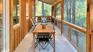 A wooden deck with a table and chairs, overlooking a forest. - Modern Beaver Valley Cabin w/ Hot Tub & Games! (Leavenworth)