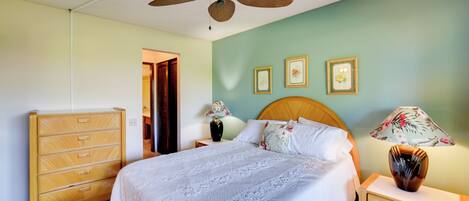 A bedroom with a bed, wooden dresser, nightstand, and a ceiling fan.