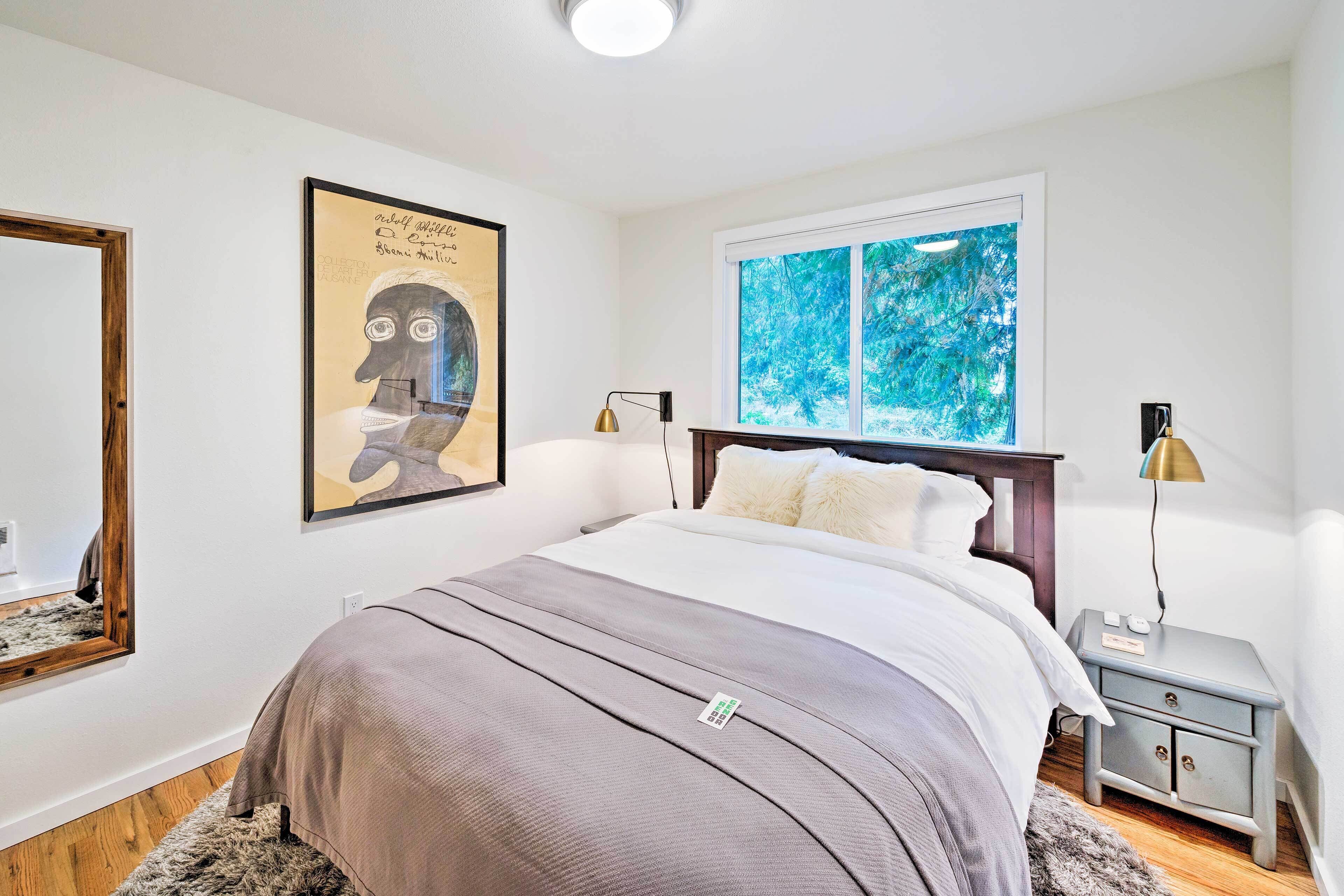A bedroom with a bed, bedside tables, a window, and a framed artwork on the wall.