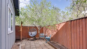 A backyard patio with a wooden fence, a swing chair, and two chairs. - Bright Bend Home w/ Patio < 3 Mi to Downtown! (Bend)