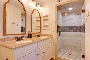A bathroom with two sinks, a large mirror, and a walk-in shower.
