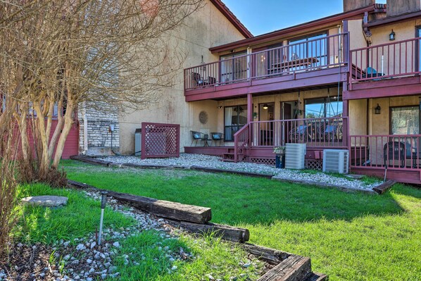 A building with a red exterior, a balcony with a metal railing, and a grassy area with a wooden fence.
