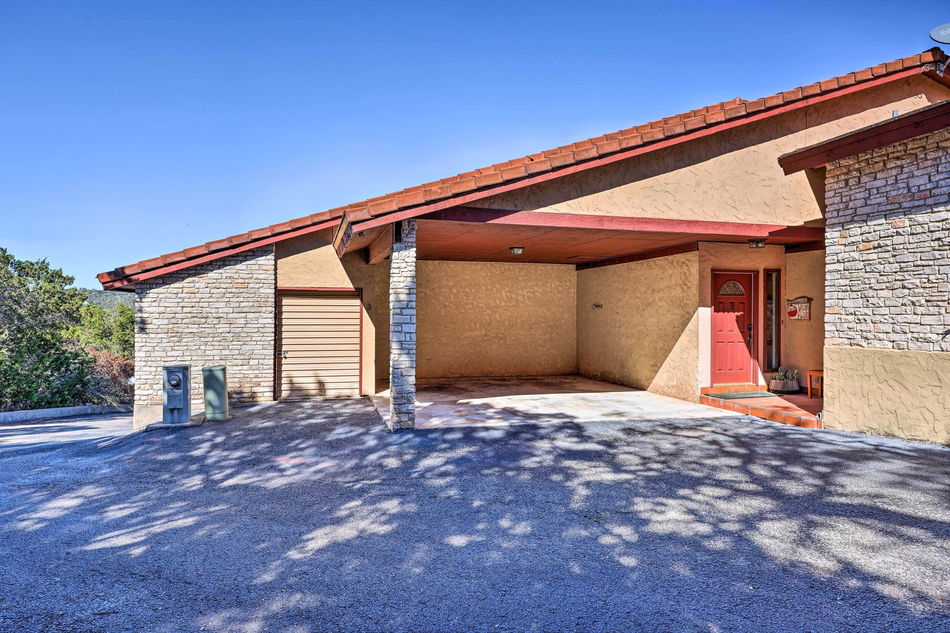 A building with a stone facade, a red door, and a covered parking area.