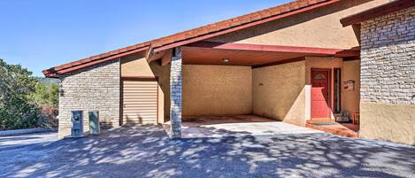 A building with a stone facade, a red door, and a covered parking area.