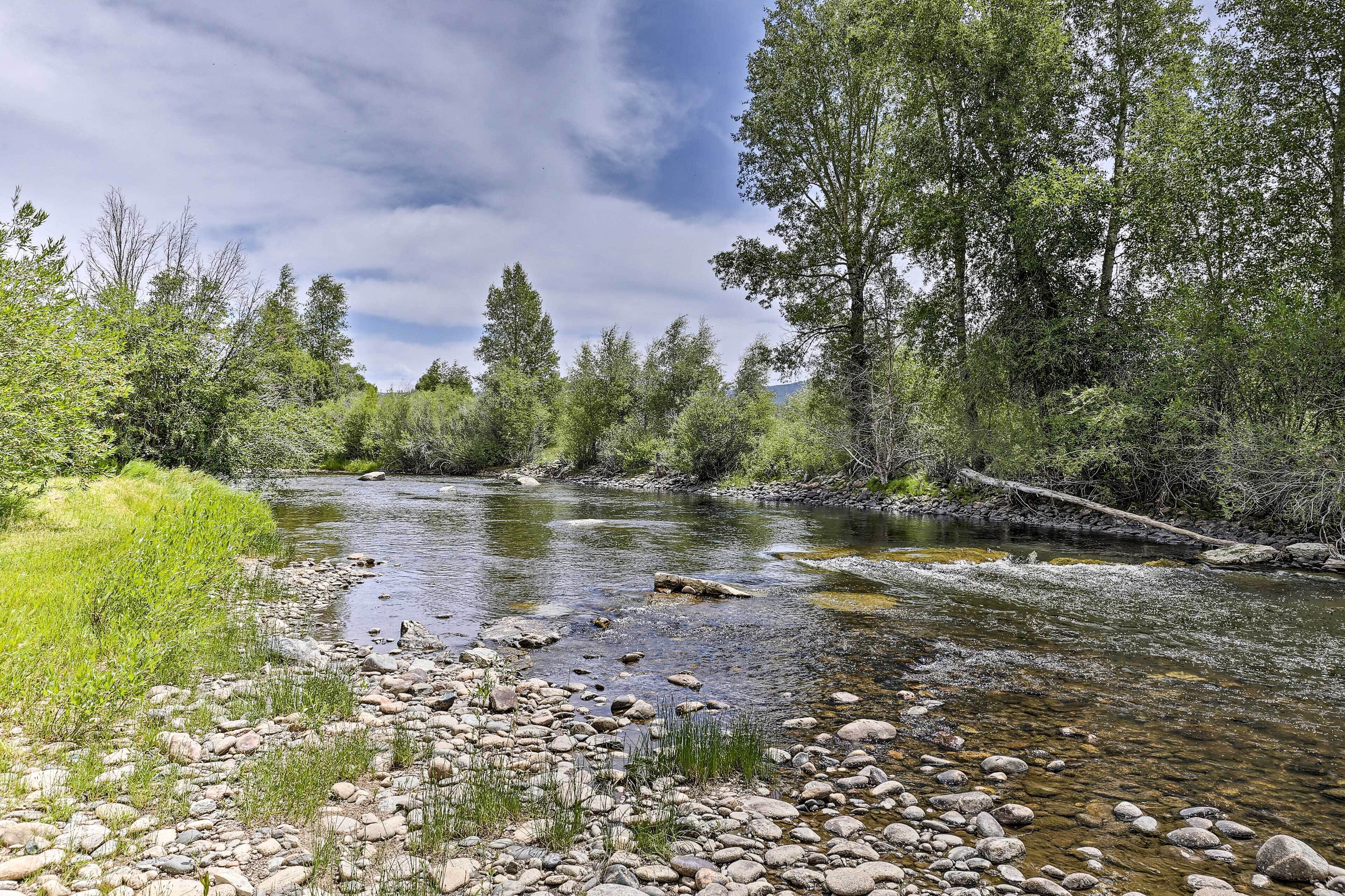A river with clear water, surrounded by rocks and greenery.