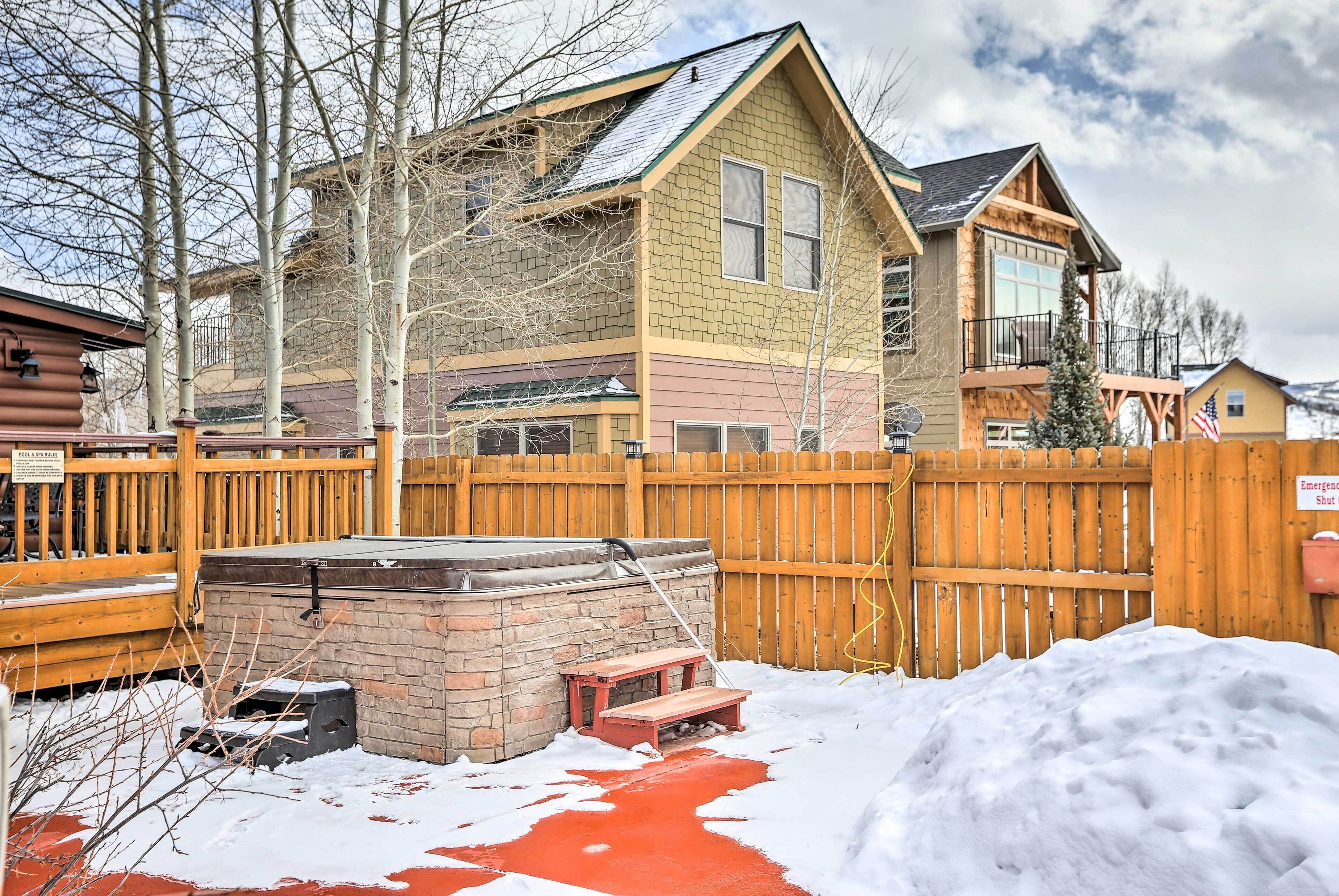 A two-story house with a stone fireplace, a wooden deck, and a wooden fence.