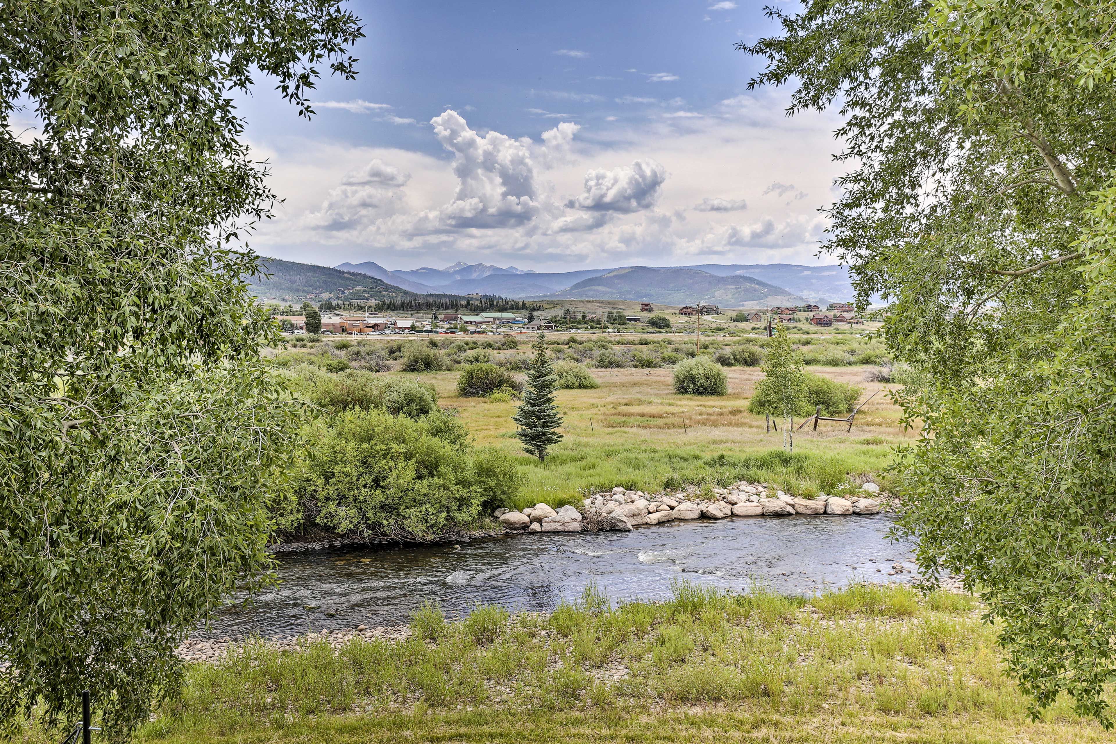 A river with a rocky bed, surrounded by greenery and trees.
