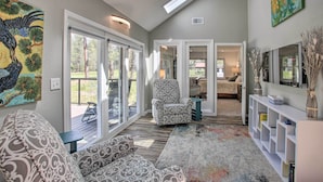 A spacious living room with a patterned armchair, a sofa, and a large rug. There are sliding glass doors leading to an outdoor deck. - All-seasons Chewelah Home: Fish, Golf & Ski! (Chewelah)