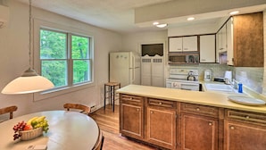A kitchen with wooden cabinets, a white countertop, and a window with a view of trees. - Door County Retreat ~ 3 Mi to Sister Bay Beach (Sister Bay)