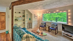A cozy living room with a large window, a sofa, chairs, a coffee table, and a TV. - Door County Retreat ~ 3 Mi to Sister Bay Beach (Sister Bay)