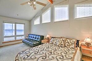 A bedroom with a bed, a black leather sofa, a ceiling fan, and large windows. - Birch Bay Waterfront Home - Steps to Beach! (Blaine)