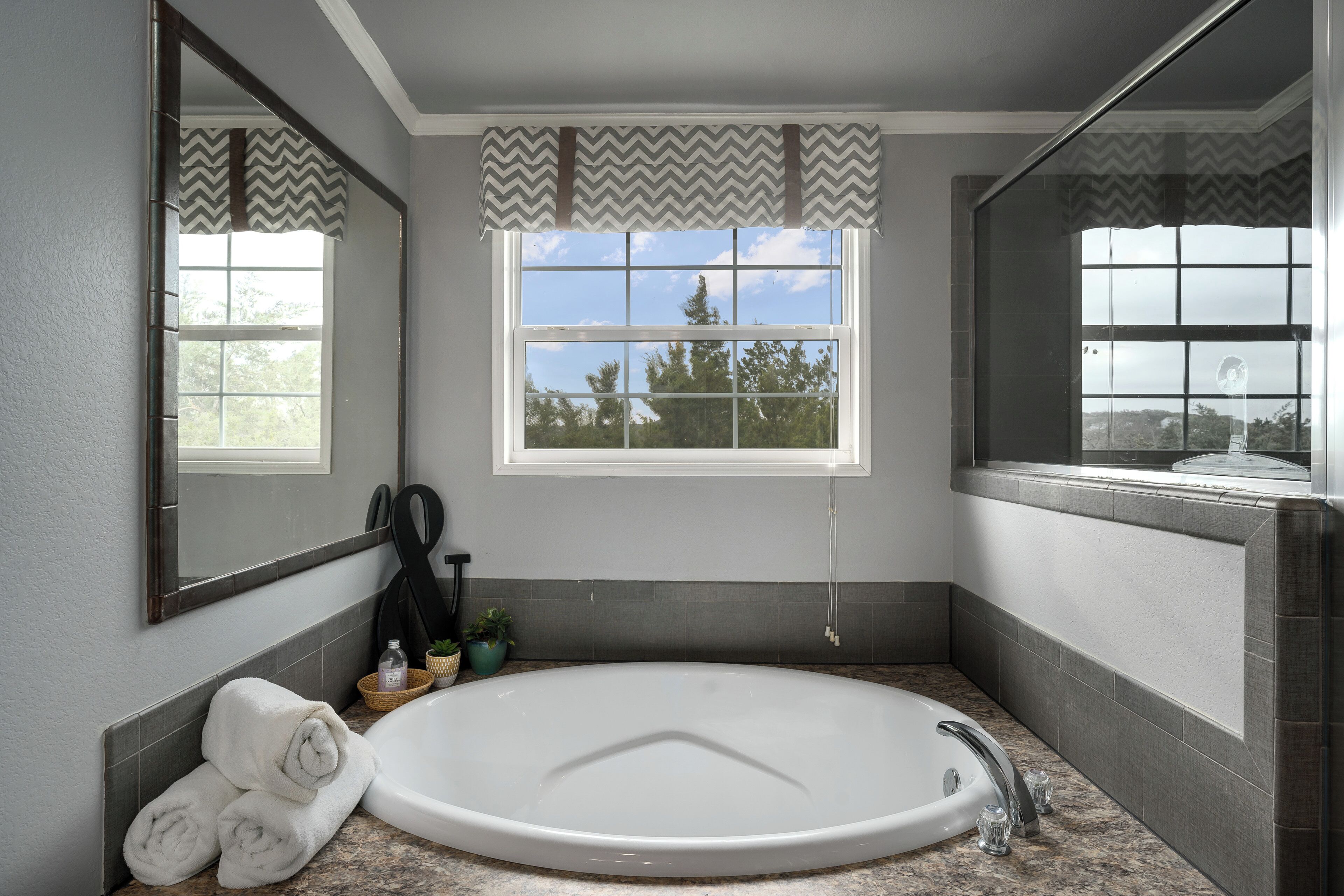 Une salle de bain avec une grande baignoire, une fenêtre donnant sur un beau paysage et un miroir.
