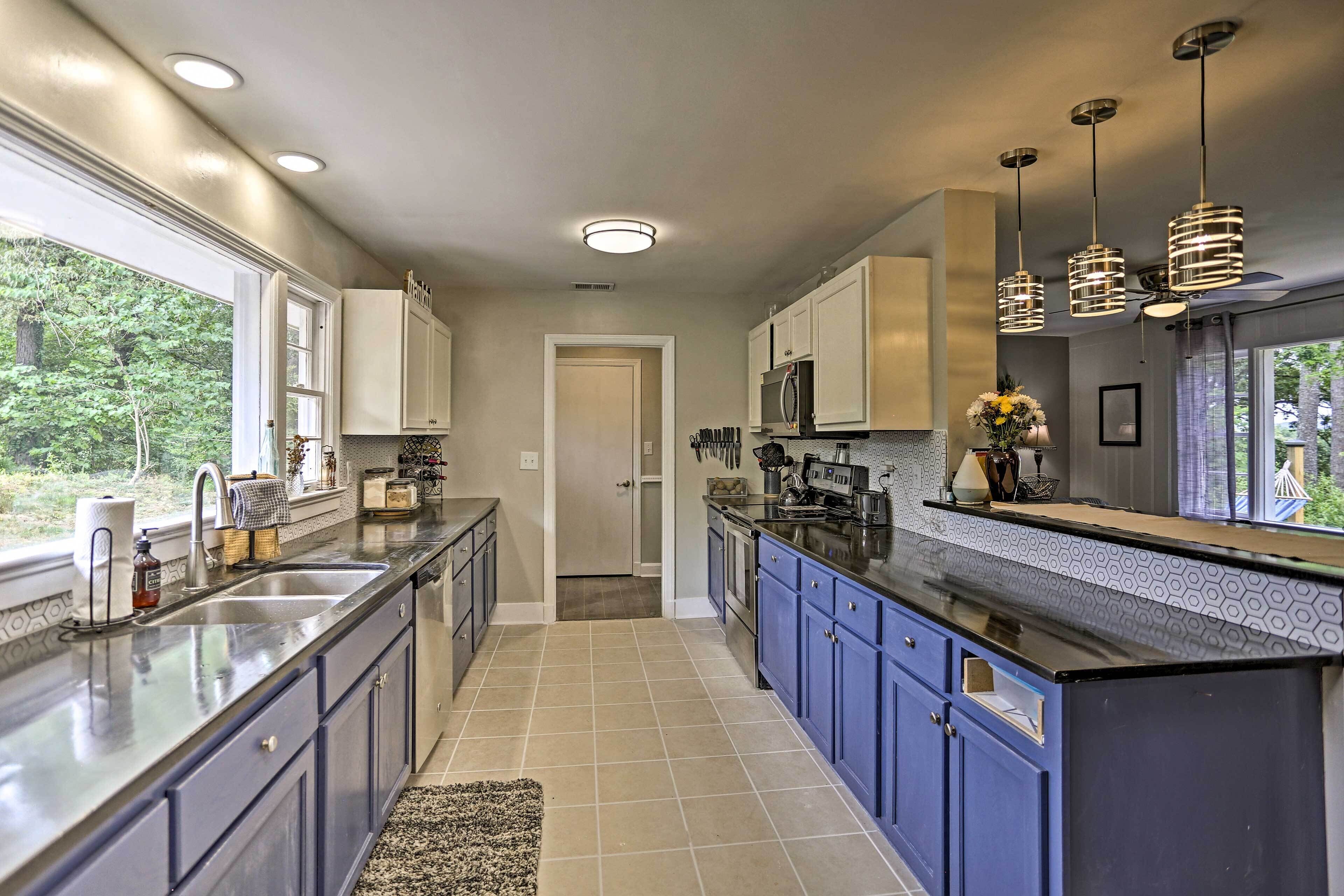 A modern kitchen with a large island, dark blue cabinets, and pendant lighting.