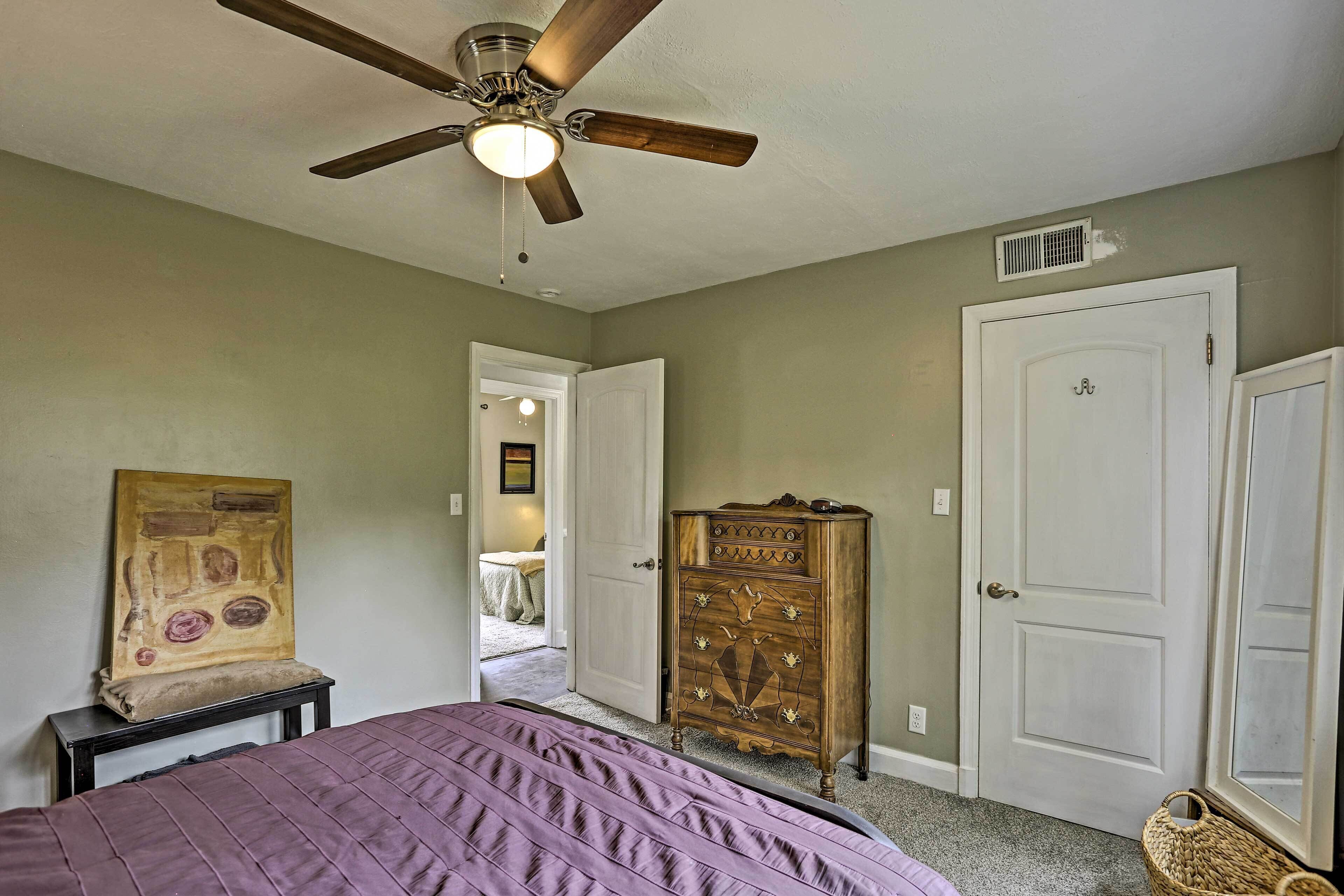 Une chambre à coucher avec un lit, un ventilateur de plafond, une commode et une porte.