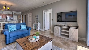 A living room with a blue sofa, wooden coffee table, and a TV on a white cabinet.