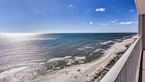 A beach view from a balcony with a clear sky and ocean.