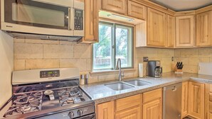 A kitchen with wooden cabinets, a gas stove, a microwave, a sink, and a dishwasher. - Well-appointed Fruita Townhome: Hike & Bike Nearby (Fruita)