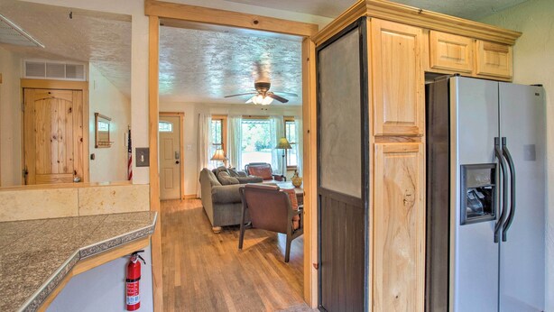 A kitchen with wooden cabinets, a refrigerator, and a dining area with a table and chairs. - Well-appointed Fruita Townhome: Hike & Bike Nearby (Fruita)