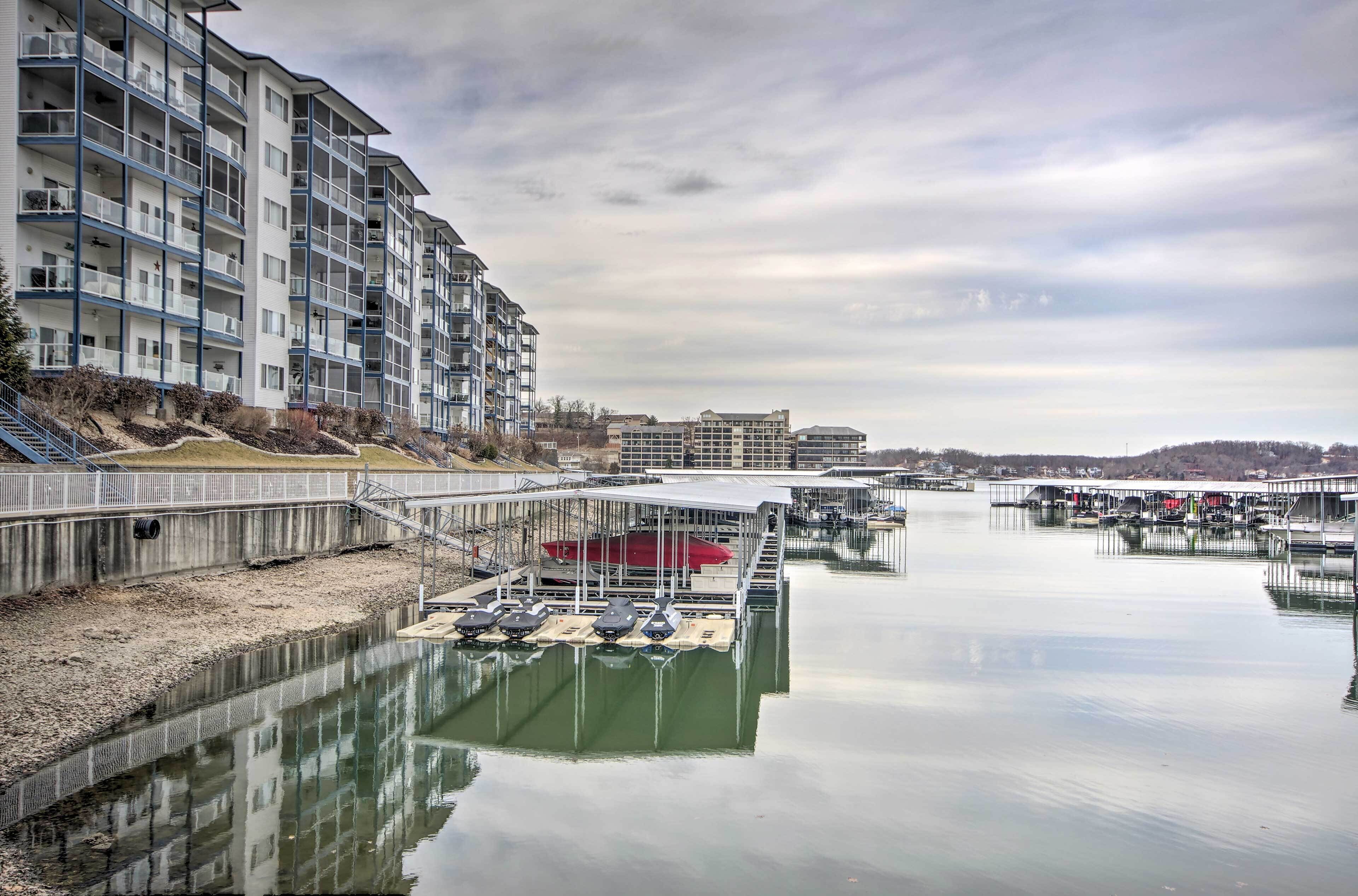 A waterfront residential building with balconies, a dock with boats, and a calm water body.