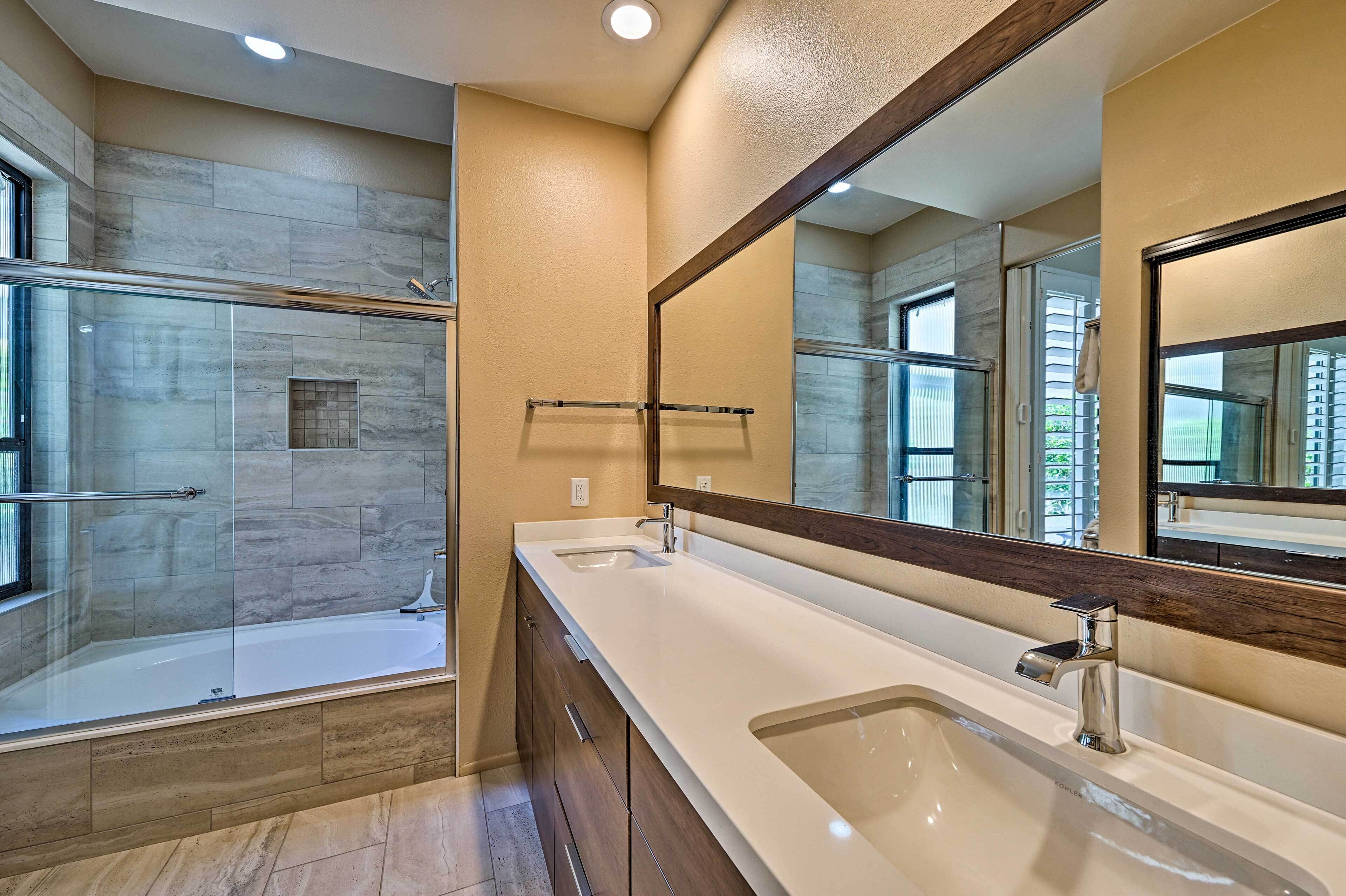 A modern bathroom with a glass-enclosed shower, a large mirror, and a double sink.