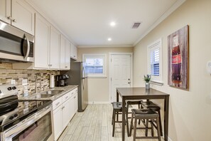 A compact kitchen with white cabinets, a stainless steel microwave, a built-in oven, and a coffee maker. - Pet-friendly Galveston Cottage < 1 Mi to Beach! (Galveston)